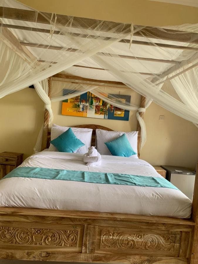 a bedroom with a canopy bed with blue and white pillows at Makna Homestay and Spa in Sidemen