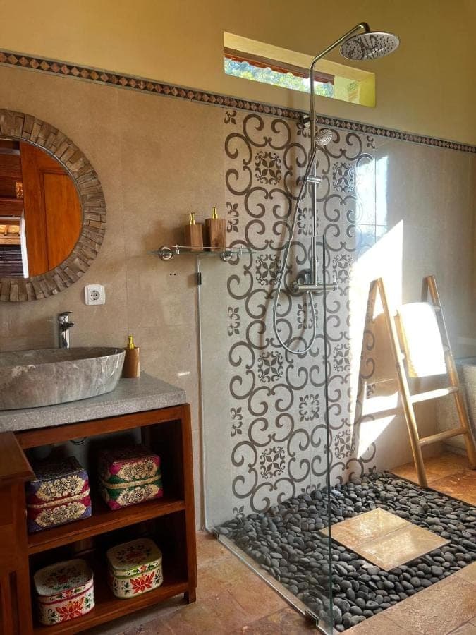 a shower in a bathroom with a sink and a mirror at Makna Homestay and Spa in Sidemen