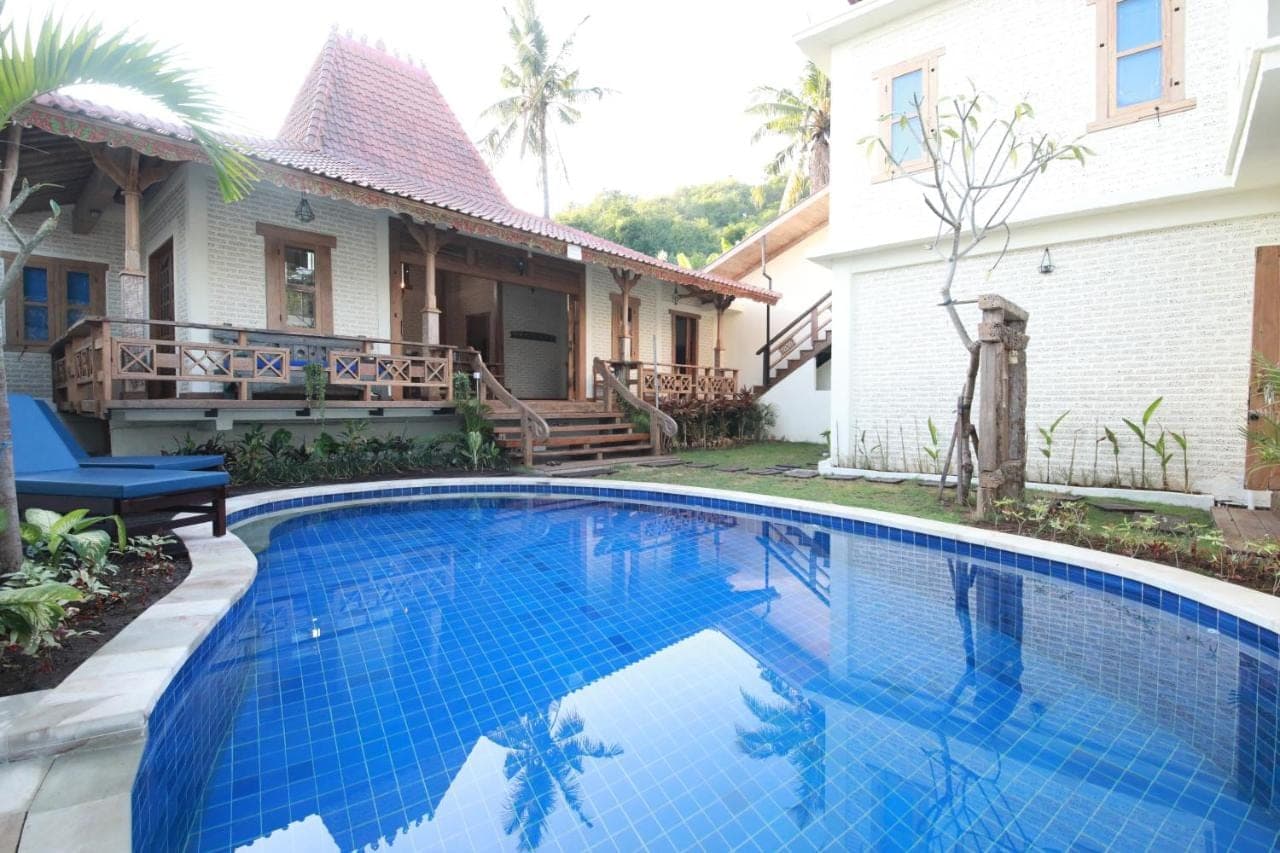 a swimming pool in front of a house at Mango Villa in Amed