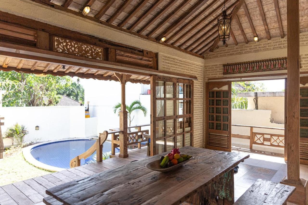 a porch with a wooden table and a bowl of fruit at Mango Villa in Amed