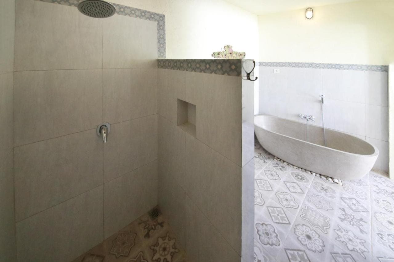 a bathroom with a tub and a shower with a sink at Mango Villa in Amed