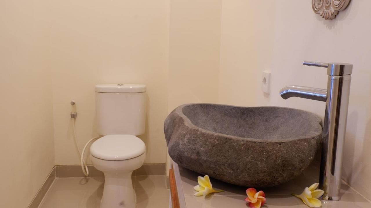 a bathroom with a bath tub next to a toilet at Boge House in Ubud