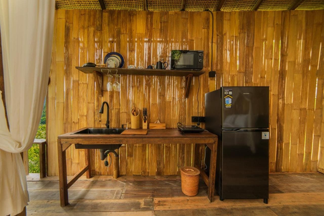 a kitchen with a refrigerator and a wooden wall at LeLangit Eco Cabin in Sidemen