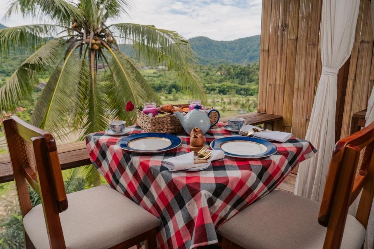 a table with a plate of food and a palm tree at LeLangit Eco Cabin in Sidemen