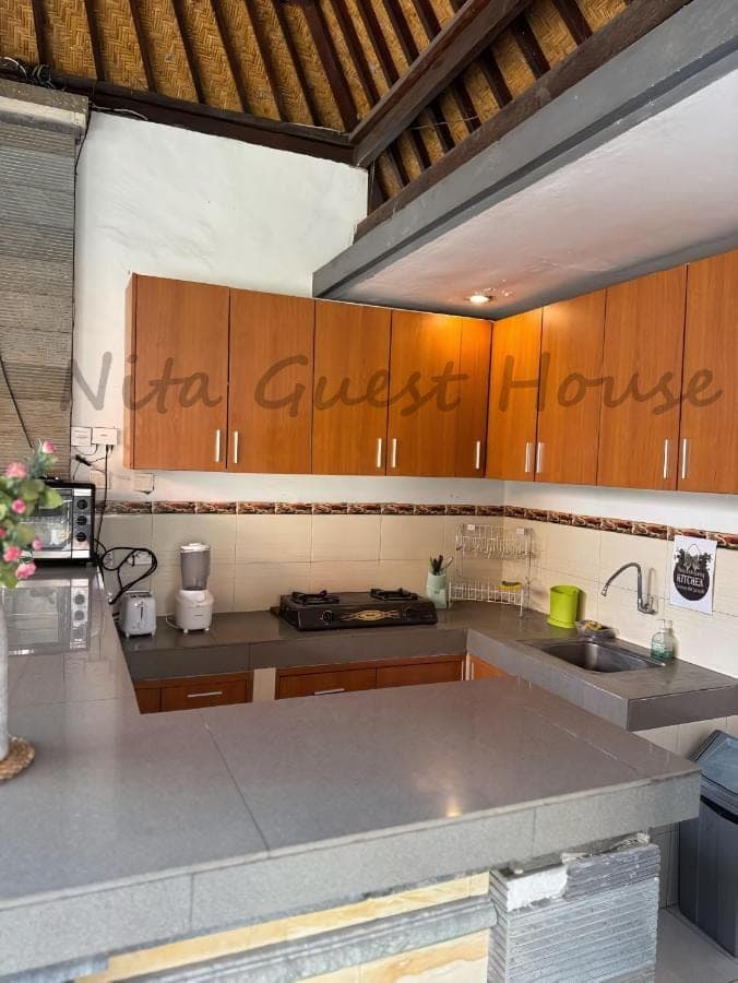 a kitchen with wooden cabinets and a counter top at Nita Guest House Bali in Canggu