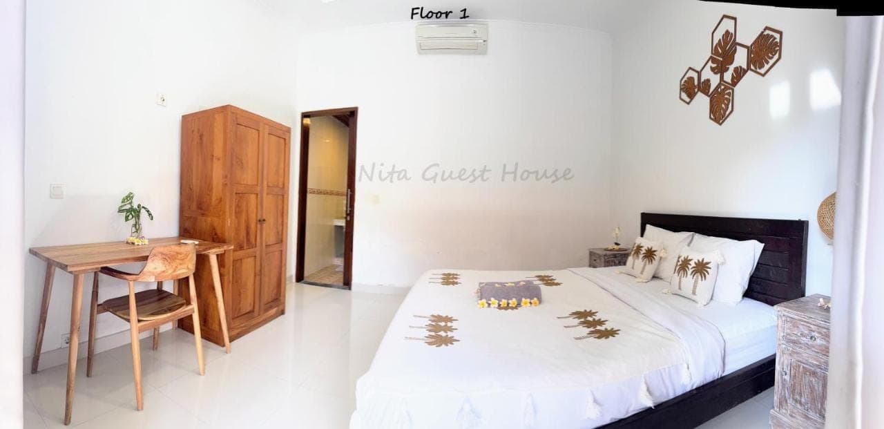 a bedroom with a bed and a desk and a table at Nita Guest House Bali in Canggu