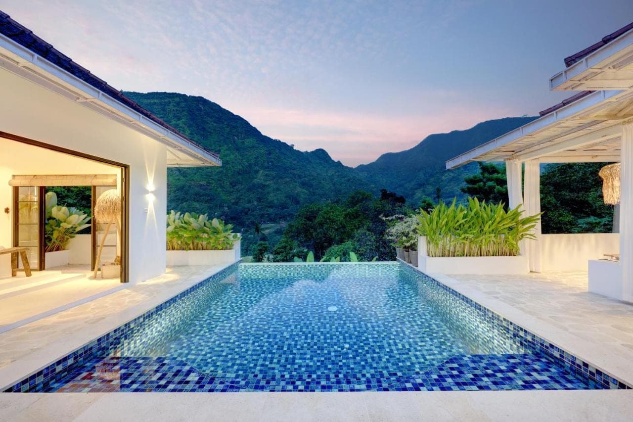 an infinity pool in a villa with mountains in the background at Tropical Habitat Bali in Amed