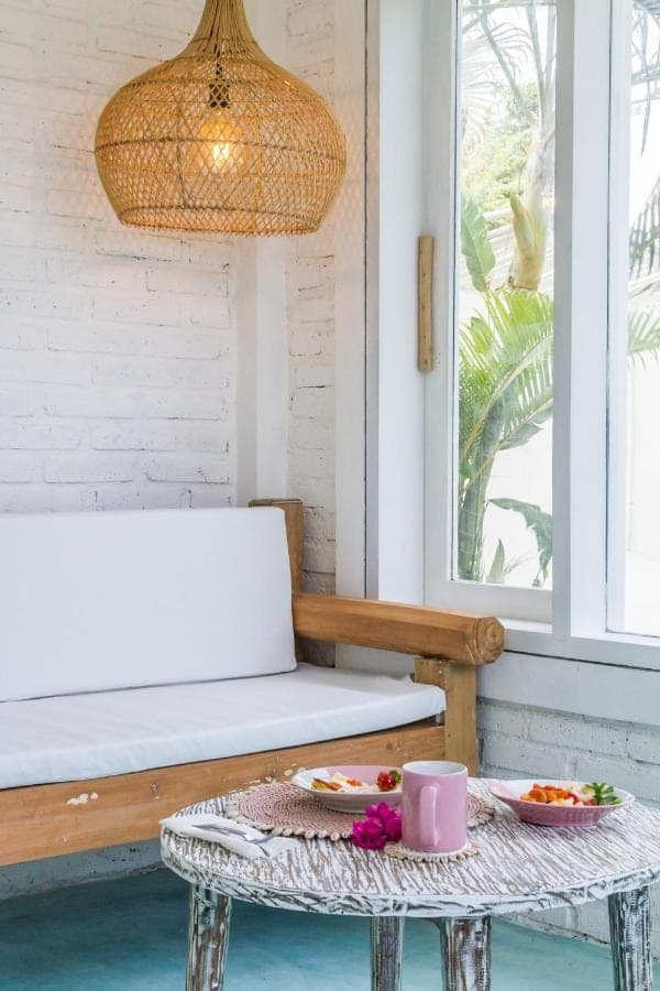 a table with a bowl of fruit and a lamp at Guru Canggu Art Hotel in Canggu