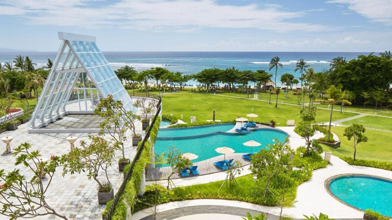 an aerial view of a resort with a swimming pool and the ocean at MERUSAKA Nusa Dua in Nusa Dua