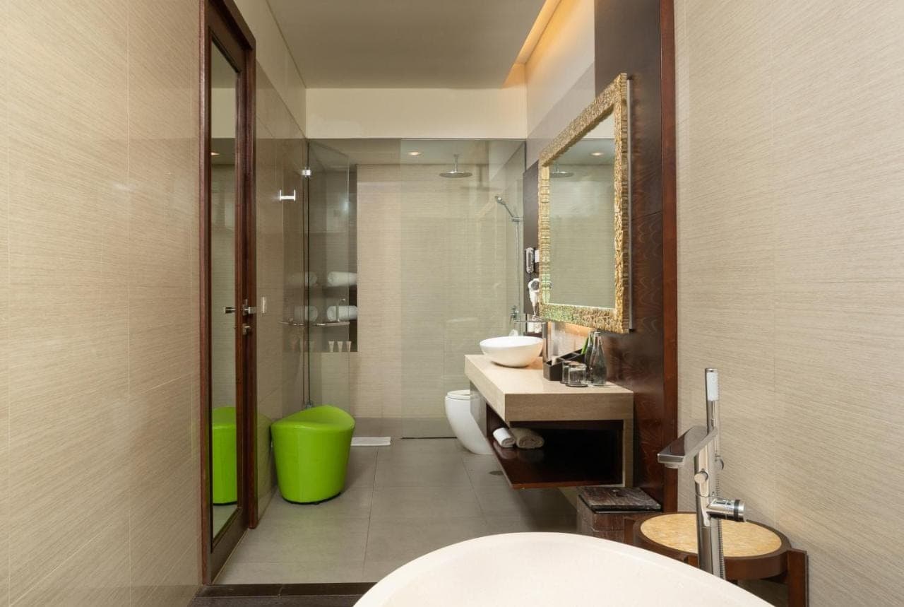 a bathroom with a sink and a toilet and a mirror at MERUSAKA Nusa Dua in Nusa Dua