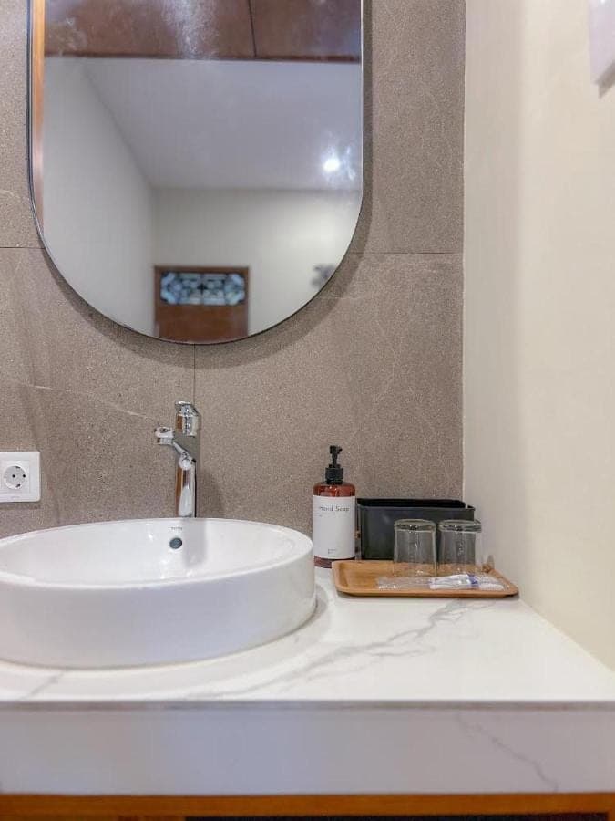 a bathroom sink with a mirror on a counter at Kaman Bali Guesthouse in Seminyak