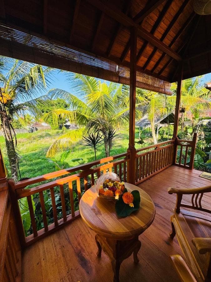 a wooden porch with a table with a bowl of fruit on it at Deva Graha Sidemen in Sidemen