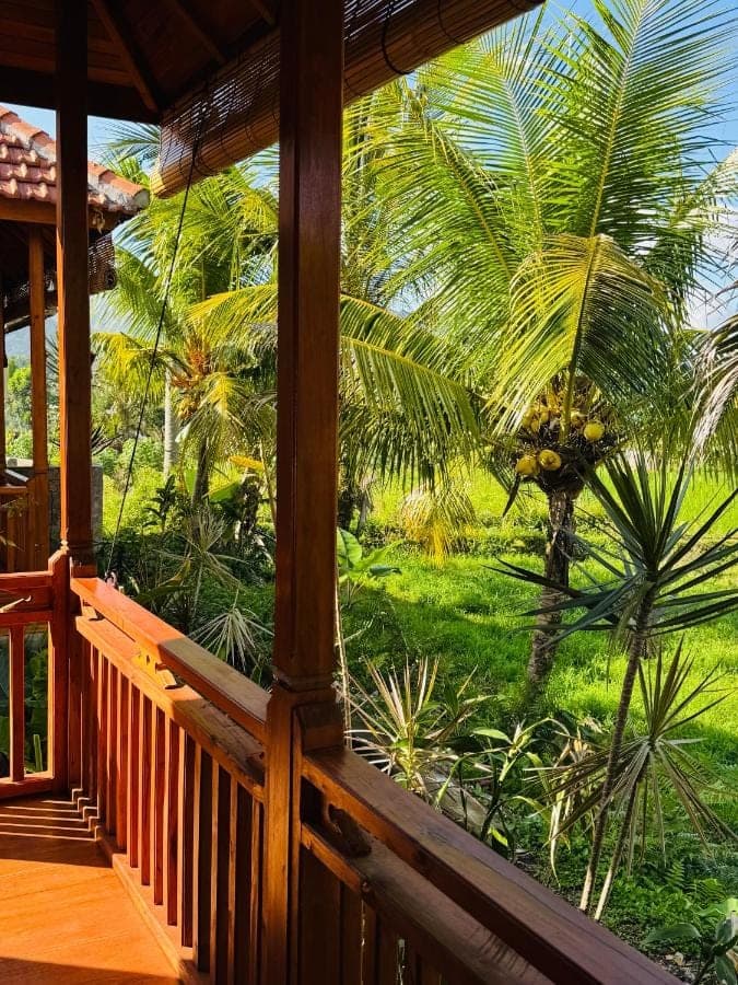 a porch with a view of a palm tree at Deva Graha Sidemen in Sidemen