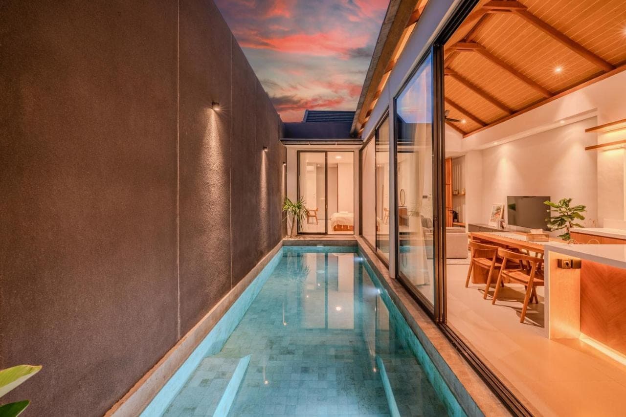 an infinity pool in a house with a kitchen and dining room at Tana Villa by UMAH - 2 Bedroom Villa and Private Pool Sanur in Sanur