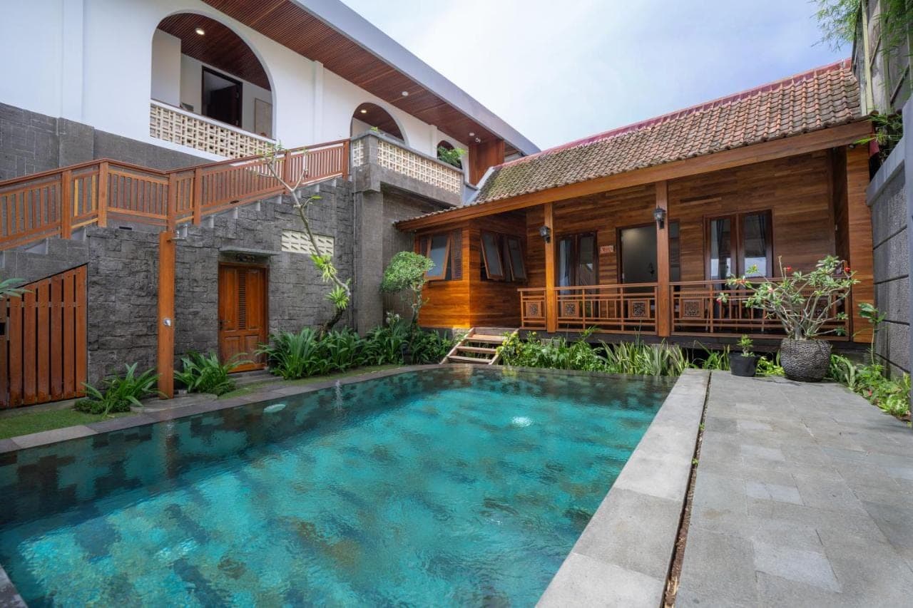 a swimming pool in front of a house at Kania Rooms & Suite Legian in Seminyak
