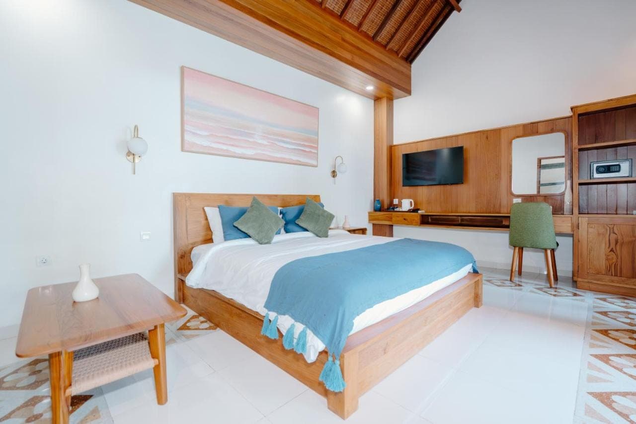 a bedroom with a bed and a desk and a tv at Kania Rooms & Suite Legian in Seminyak
