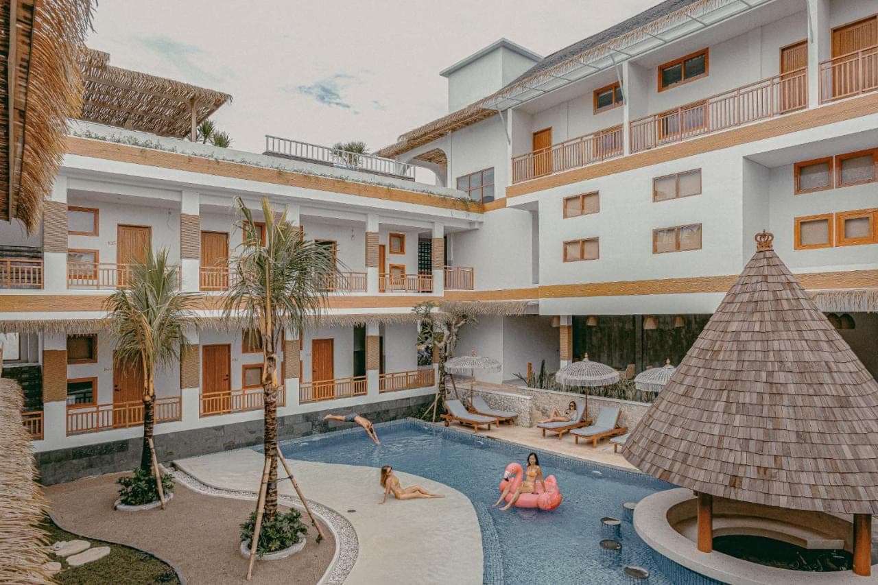 a hotel with a swimming pool with people in it at Roomates Beach Hostel Canggu by Ini Vie Hospitality in Canggu