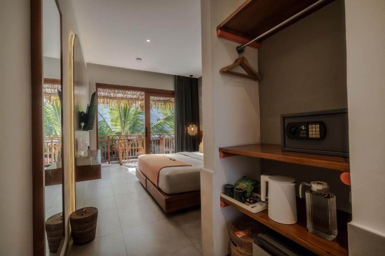 a hotel room with a bed and a balcony at Roomates Beach Hostel Canggu by Ini Vie Hospitality in Canggu
