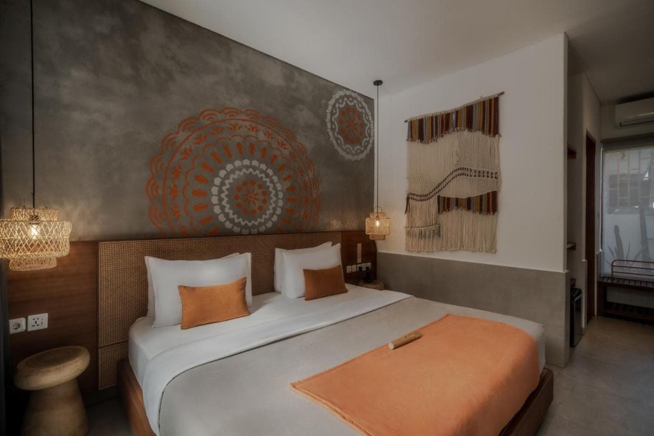 a bedroom with a large white bed with an orange blanket at Roomates Beach Hostel Canggu by Ini Vie Hospitality in Canggu