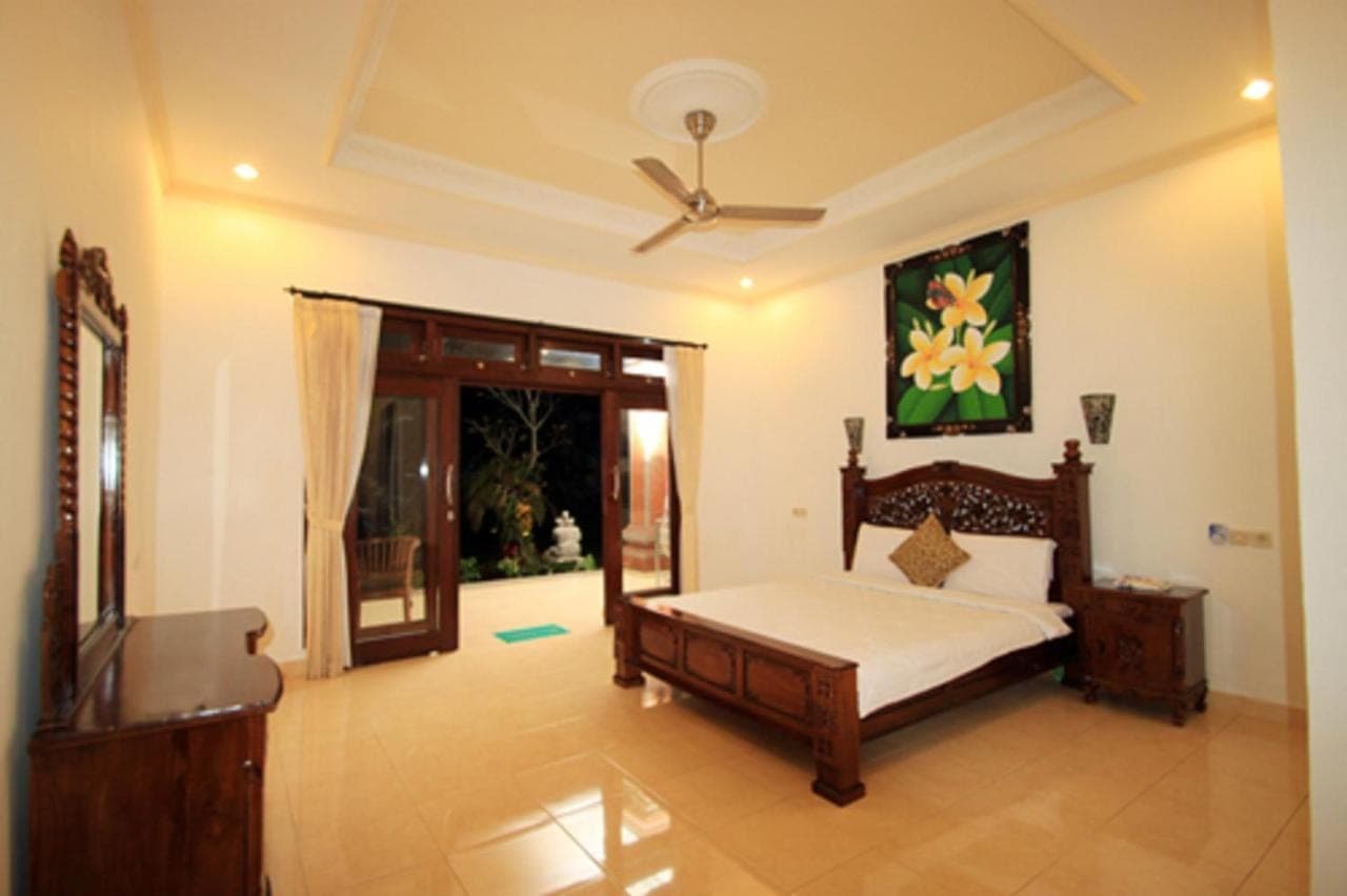 a bedroom with a bed and a ceiling fan at Tanah Semujan Ubud in Ubud