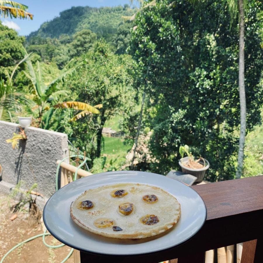 a pizza sitting on a plate on a table at Pondok Taksu Homestay Sidemen in Sidemen