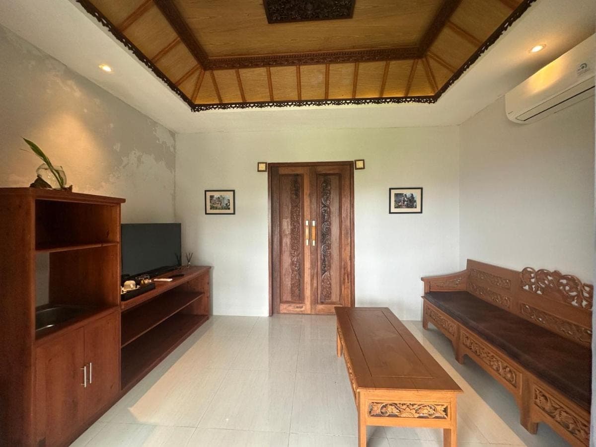 a living room with a couch and a wooden table at KETUT JOGLO GUEST HOUSE in Nusa Dua