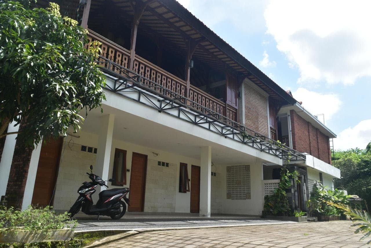 a scooter parked outside of a building with a balcony at KETUT JOGLO GUEST HOUSE in Nusa Dua