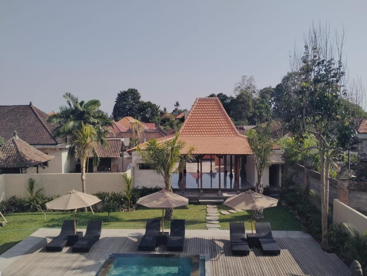 a resort with a pool and chairs and umbrellas at Londo House in Ubud