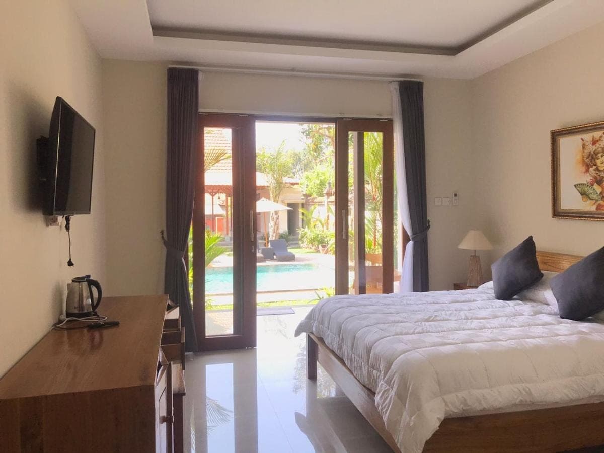 a bedroom with a bed and a sliding glass door at Londo House in Ubud