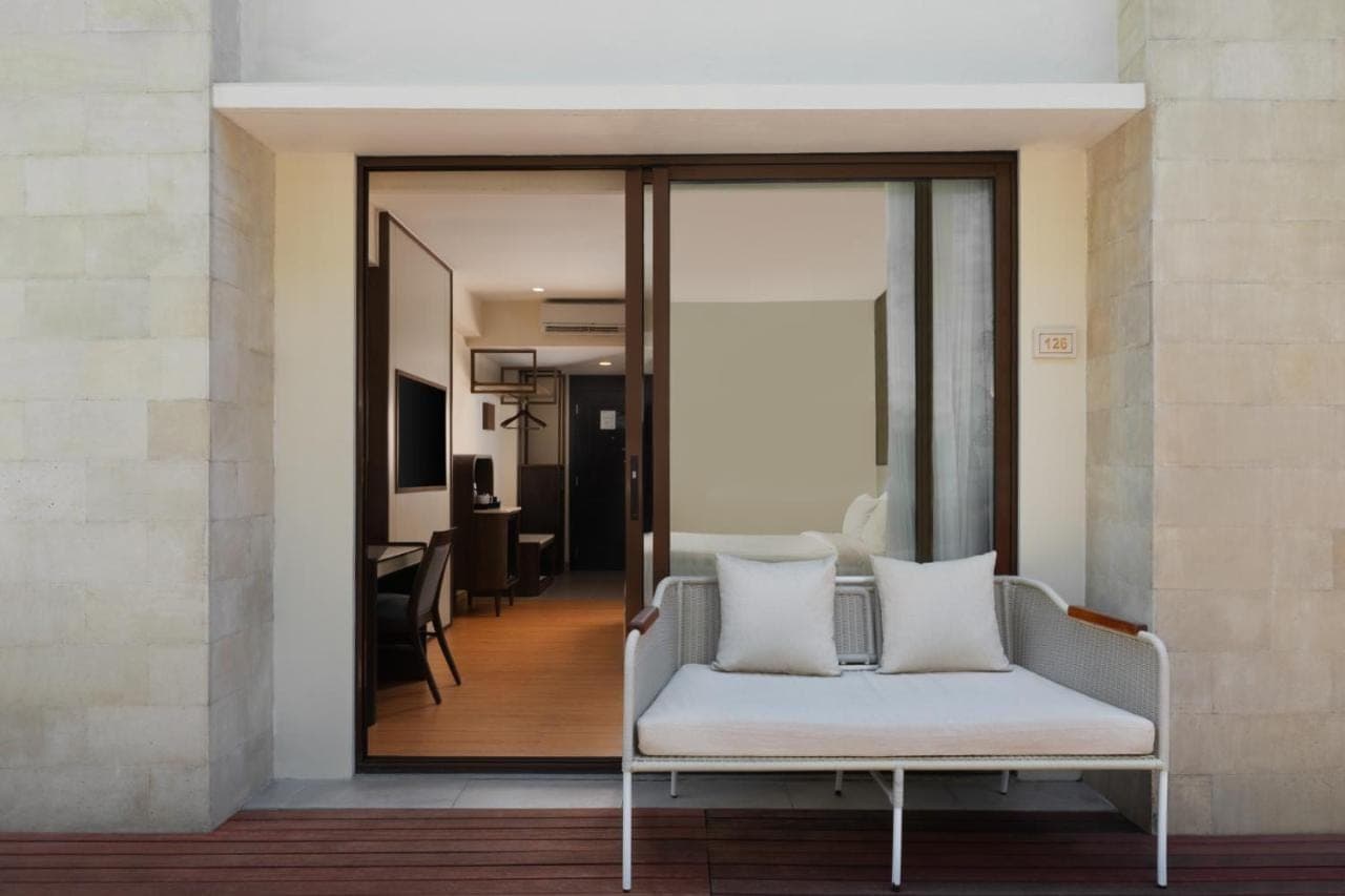 a room with a white couch and a mirror at Aston Kuta Hotel and Residence in Kuta
